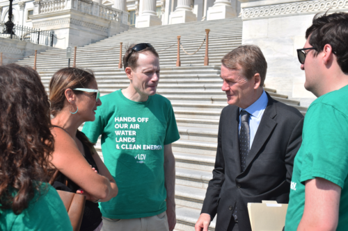 LCV staff in green shirts talking to Senator Michael Bennet (CO) on the steps of the U.S. Capitol.