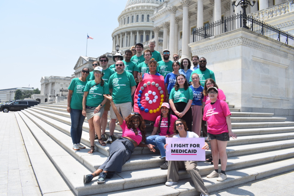 A group of people in green and pink shirts pose on the steps of the U.S. Capitol building.