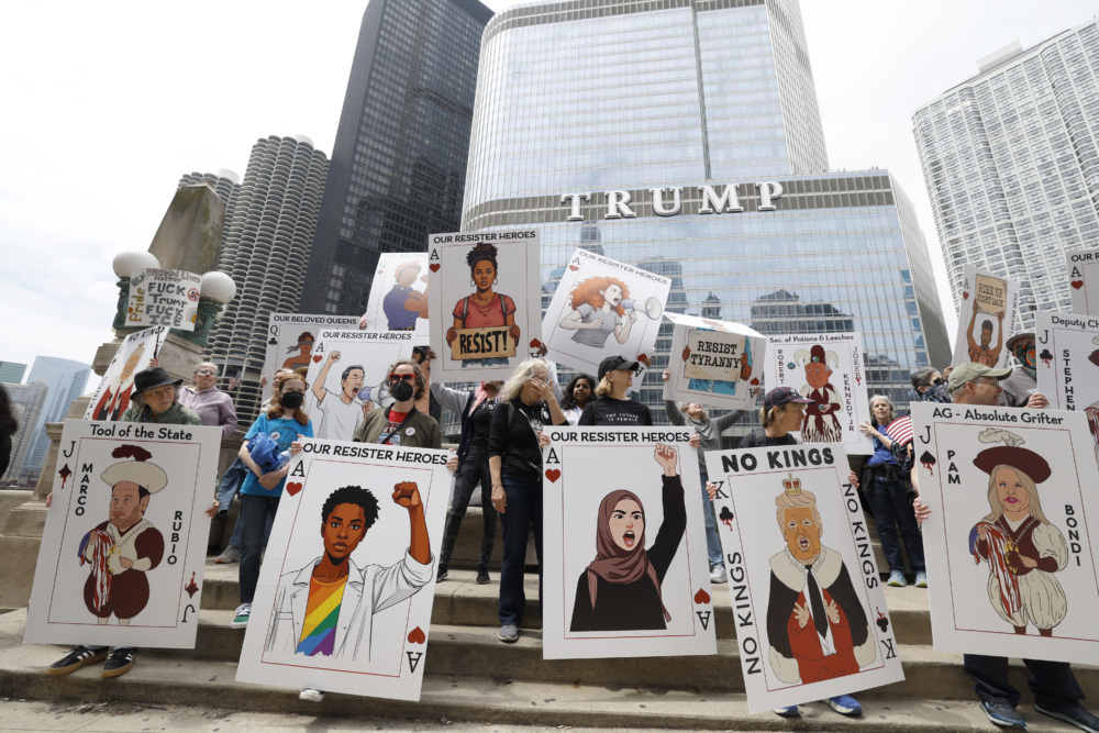 Protesters holding playing card themed signs criticizing the Trump administration stand in front of Trump tower in Chicago.