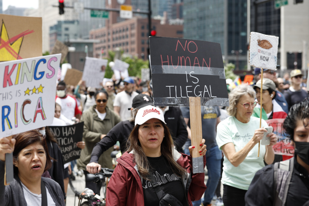 Protesters carrying signs in the streets of Chicago. One sign reads "No human is illegal."