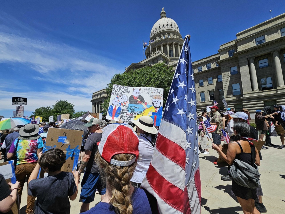 Protesters carrying signs and American flags outside the Idaho state capitol building.