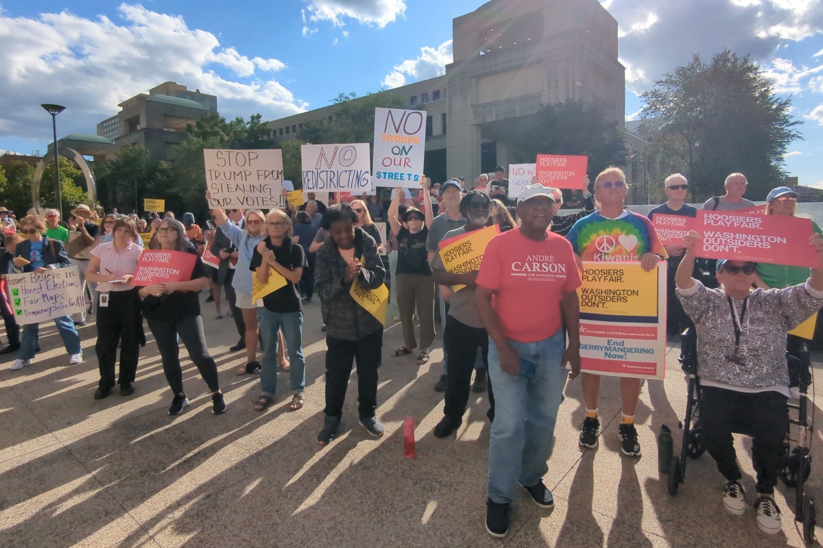 A group of protestors hold signs against redistricting.