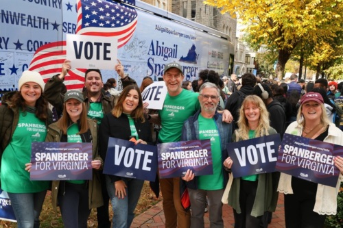 A smiling group wearing green t-shirts poses with posters reading "Vote" and "Spanberger for Virginia."