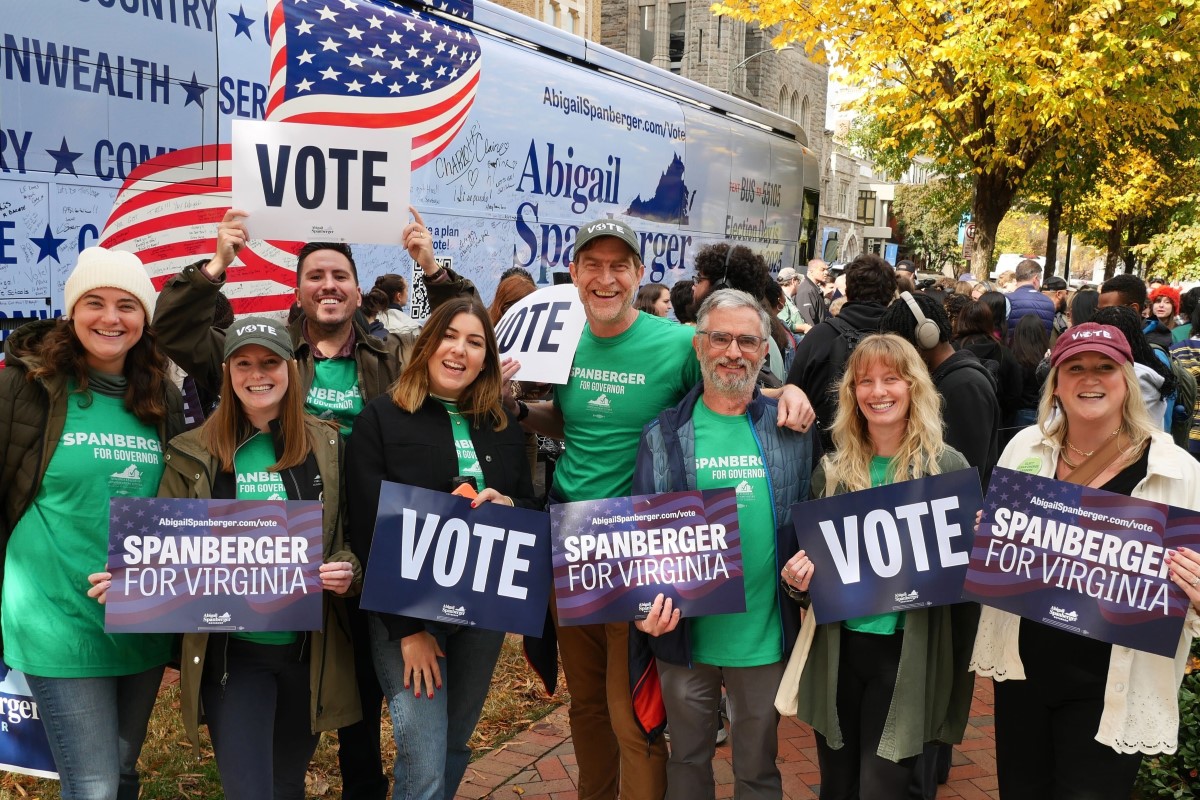 A smiling group wearing green t-shirts poses with posters reading "Vote" and "Spanberger for Virginia."