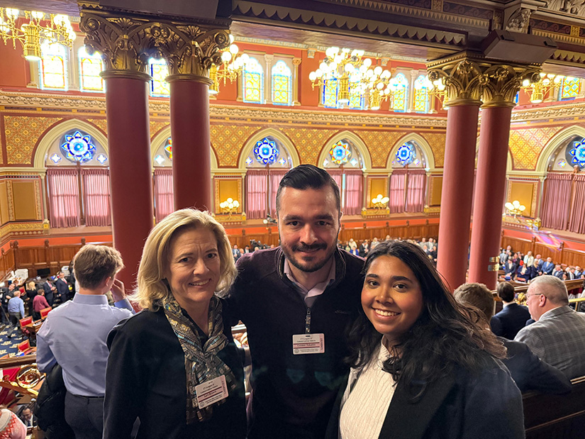 Three people pose for a photo inside the Connecticut legislature.