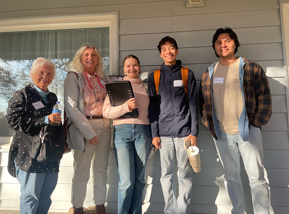 Five people stand outside in front of a building.
