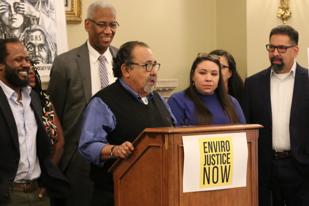 Rep. Grijalva speaks at a podium surrounded by smiling supporters.