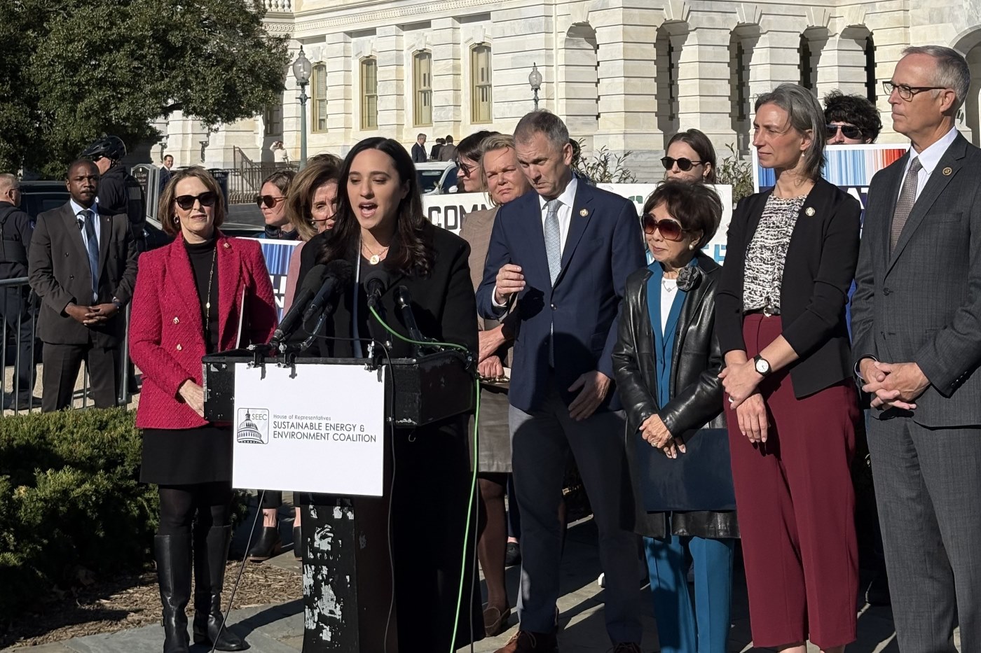 A woman speaks at a podium at a presser outside of the Capitol building.