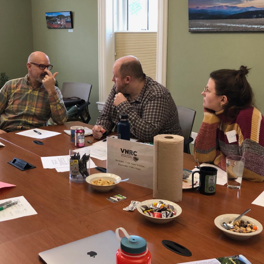 Candidate Academy participants speak to on another around a table
