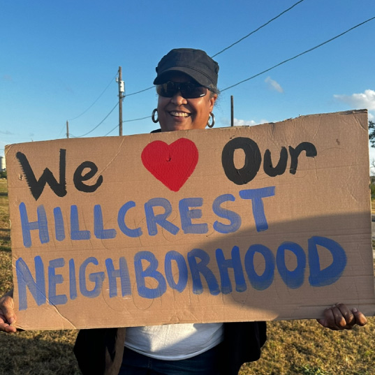 Monna Lytle holds up a sign that reads "we love our Hillcrest neighborhood"