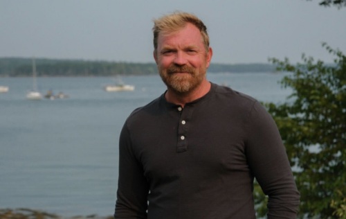 Graham Platner stands in front of a body of water.