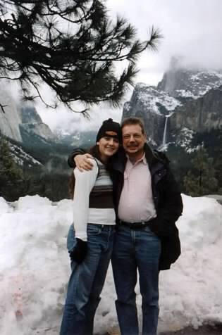 A man and woman with their arms around in other in a snowy landscape.