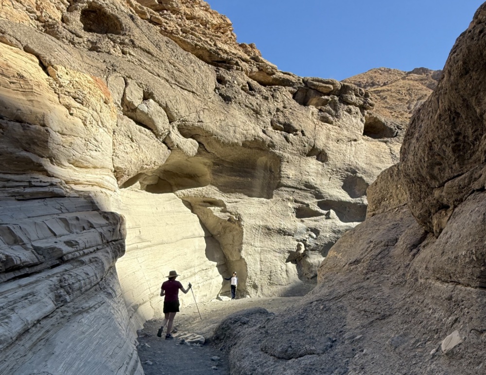 A person walks through a large rock formation.