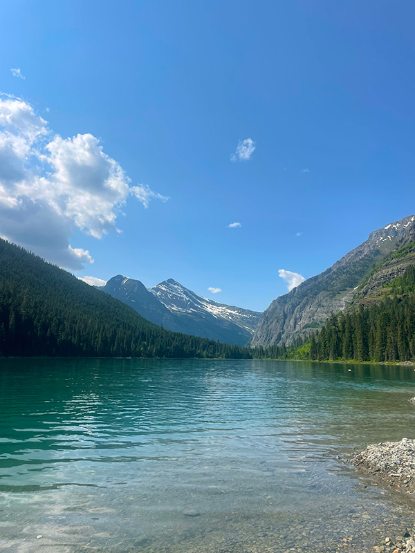 A body of water with trees on both sides and a blue sky.