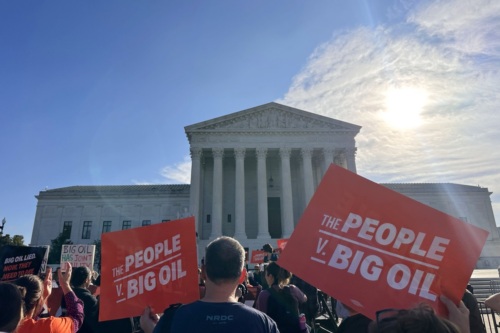 A crowd rallies in front of the Supreme Court building, holding signs reading "The People v. Big Oil" and "Big Oil Lied, Now They Need to Pay."